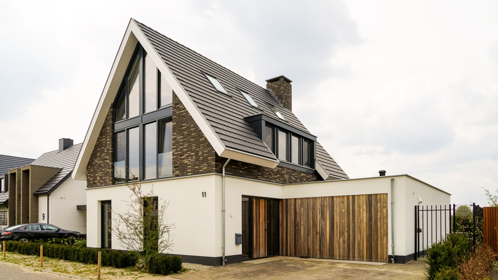 Gerealiseerd van woning met wit stucwerk, houten accenten en overstekend zadeldak 1