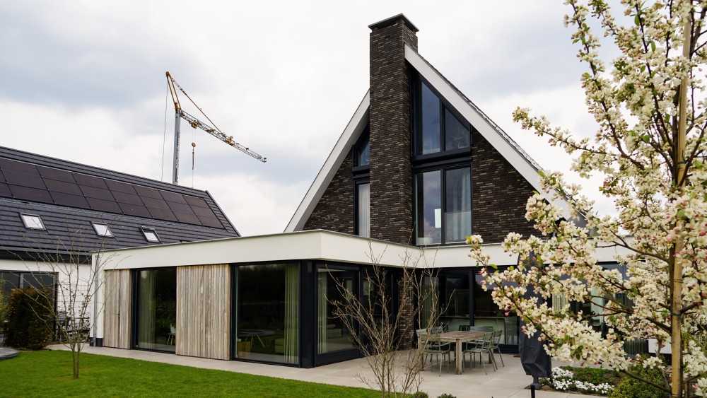 Gerealiseerd van woning met wit stucwerk, houten accenten en overstekend zadeldak 3