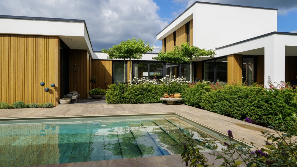 Gerealiseerd van kubistische woning met wit pleisterwerk, houtaccenten en strak vormgegeven buitenruimte 1