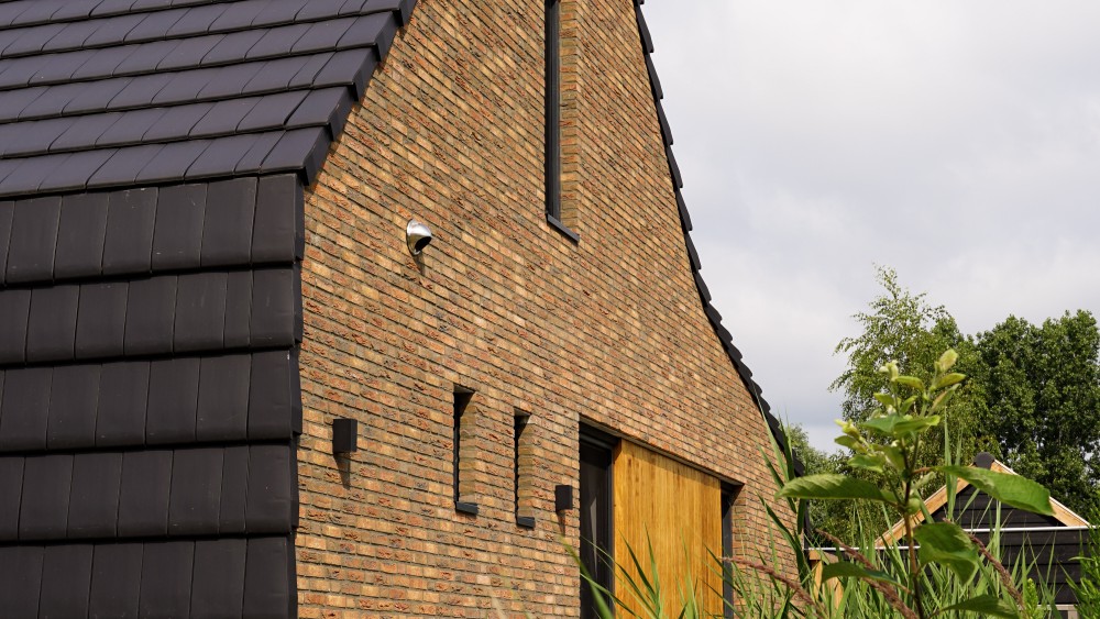 Gerealiseerd van schuurwoning met zadeldak, donkere gevelsteen en houten accenten 2