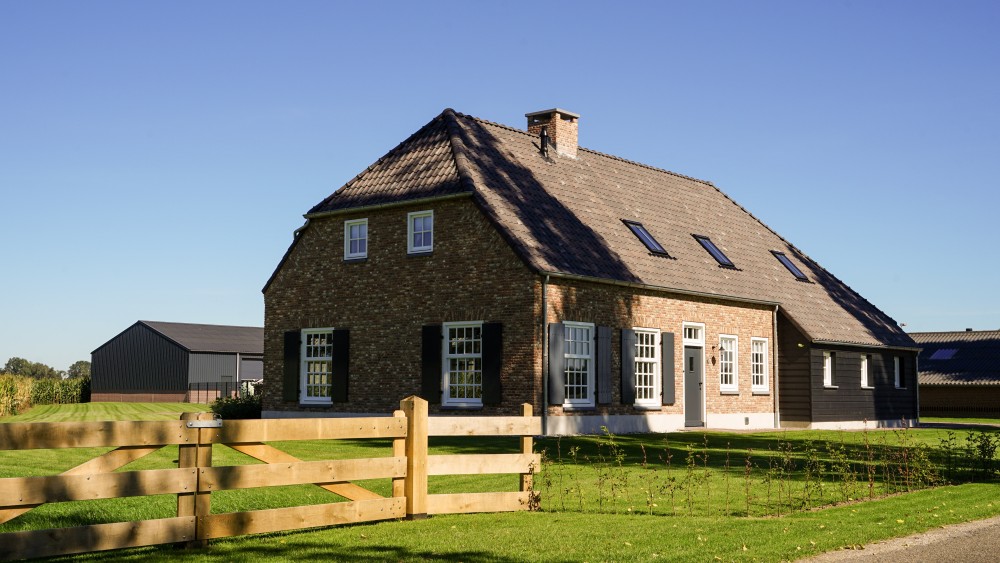 Gerealiseerd van woning met metselwerk gevel, gegolfde dakpannen en houtaccenten onder wolfsdak 1