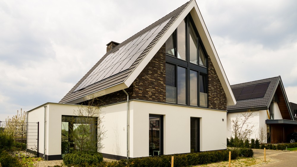 Gerealiseerd van woning met wit stucwerk, houten accenten en overstekend zadeldak 2